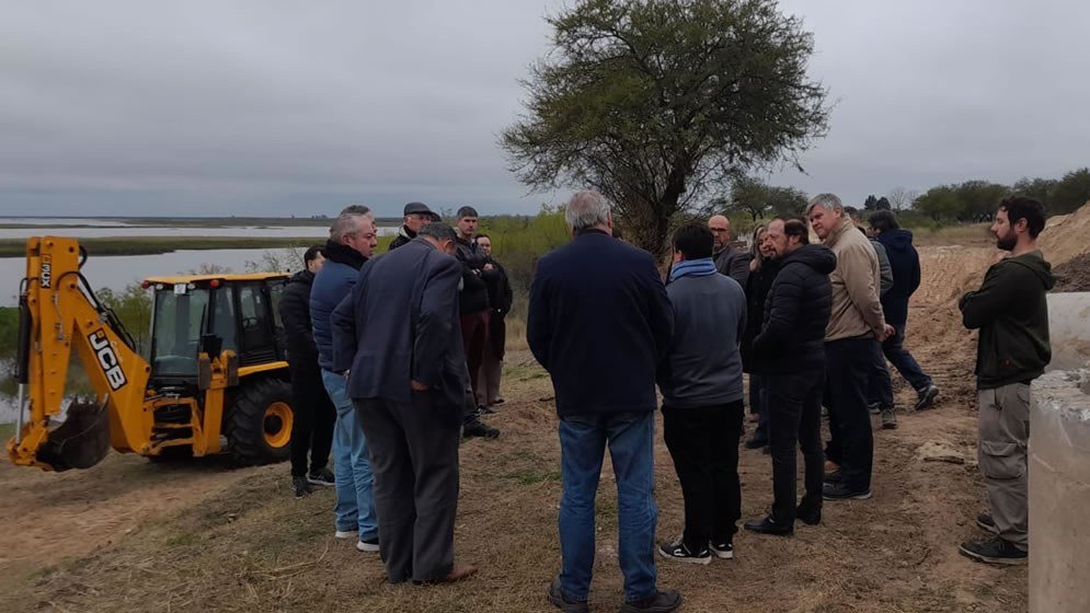 Un grupo de autoridades recorre la zona de obras de la defensa junto a una retroexcavadora y la laguna
