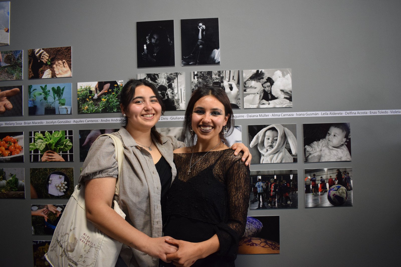 Dos jóvenes autoras posan junto a sus fotografías en la muestra La luz que nos mira