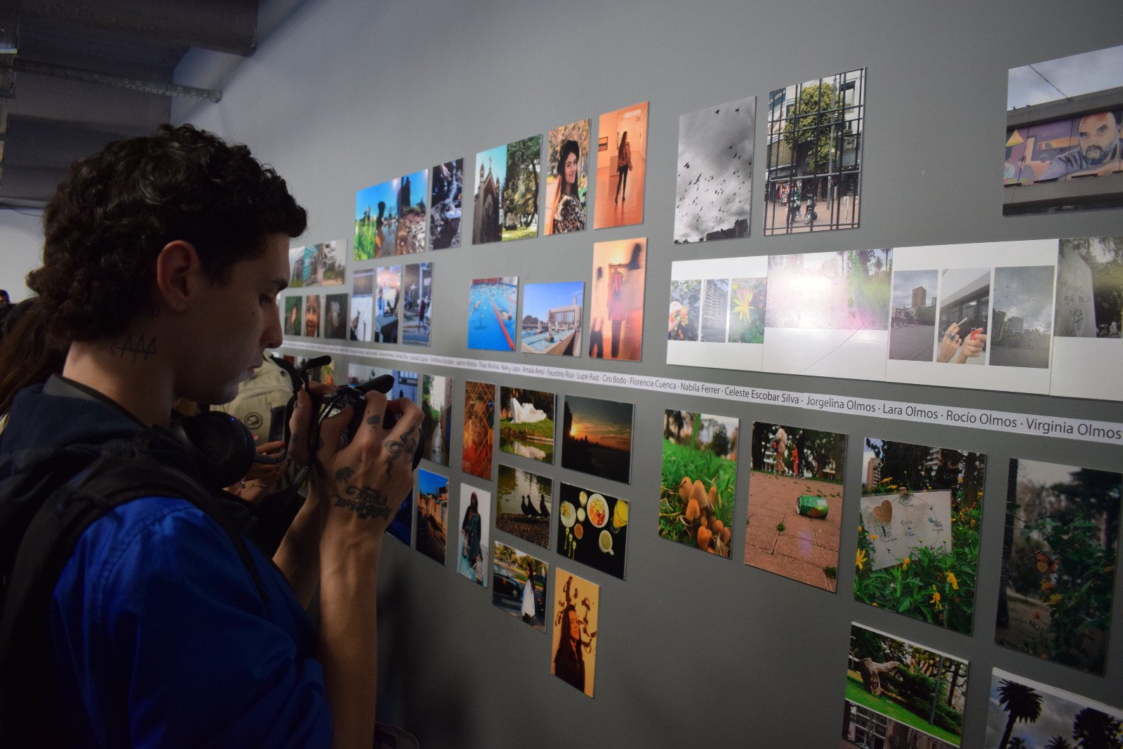 Un visitante fotografía la pared de imágenes de la muestra
