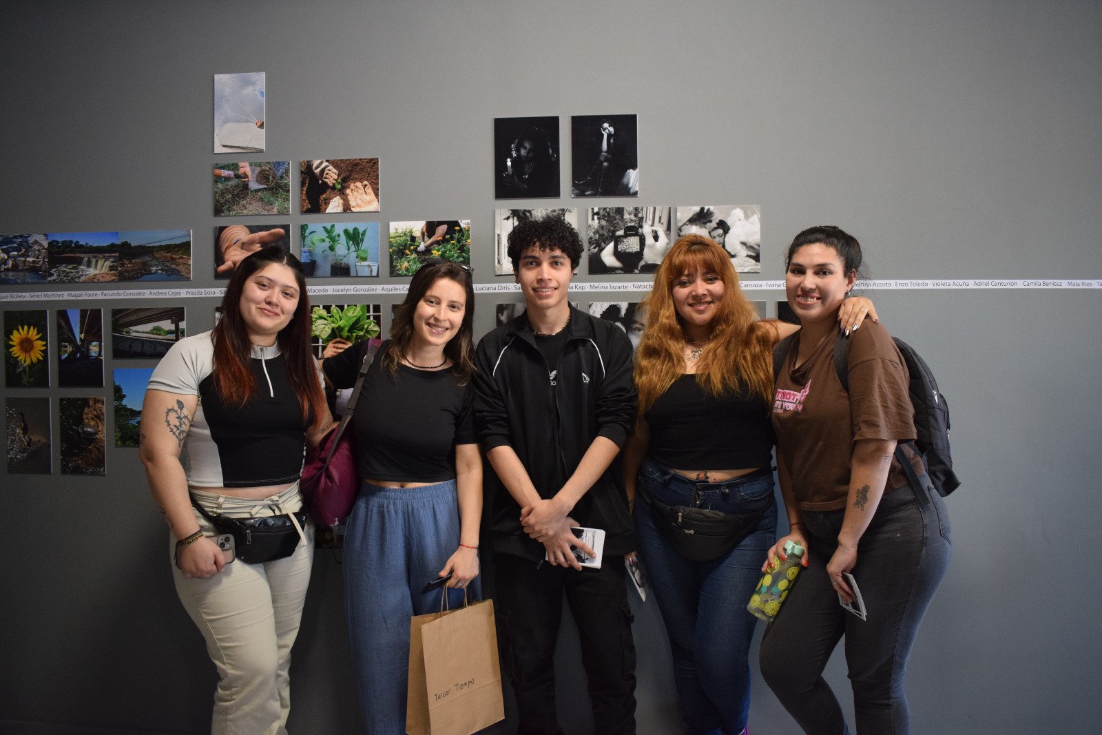 Un grupo de jóvenes autores frente a la pared de fotografías de la muestra